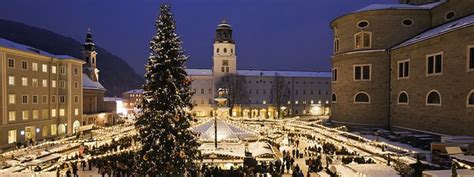 A Large Christmas Tree Is In The Middle Of A Snowy Town Square With