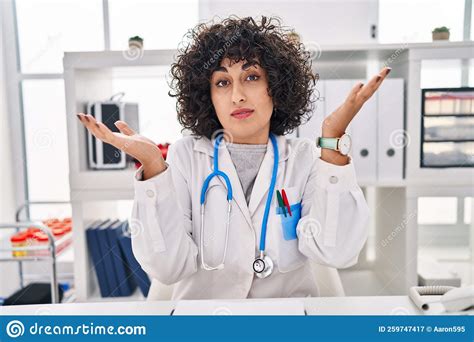 Young Brunette Woman With Curly Hair Wearing Doctor Uniform And Stethoscope Shouting And