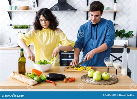 Young Cute Smiling Couple Cooking Together At Kitchen At Home Young People Are Preparing A