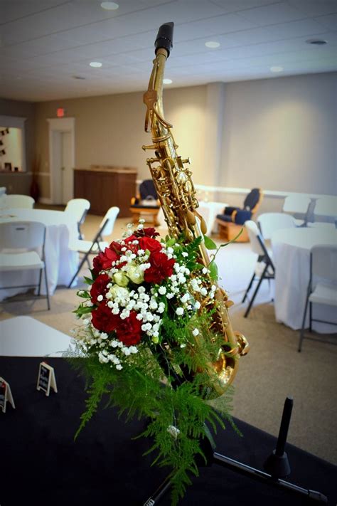 A Bouquet Of Flowers Sits Next To A Saxophone On A Table In An Empty Room