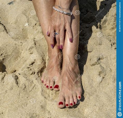 Woman Legs With Red Pedicure Relaxing On The Sand The Hand Strokes The Leg Stock Image Image