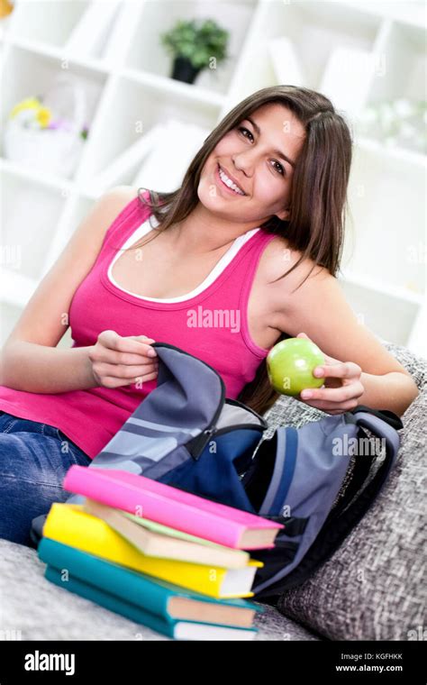 Teenage Girl Packing Books For School In Book Bag At Home Stock Photo