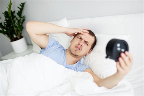 Sleepy Man Waking Up Early After Hearing Alarm Clock Signal Stock Photo