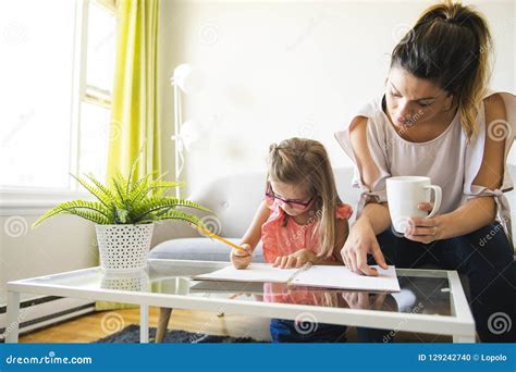 Mother Helping Her Daughter During Her Homework In The Living Room