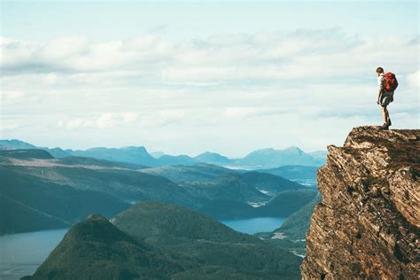 Man explorer standing on cliff alone mountain summit over ...