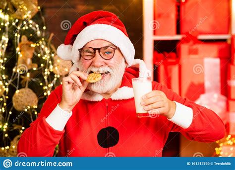 Santa Make Funny Face And Picking Cookie. Santa Claus In Santa Hat. Santa Picking Cookie And 