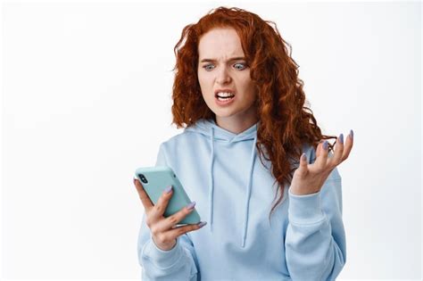 Free Photo Angry And Annoyed Redhead Woman Grimacing Mad Staring At Smartphone Screen
