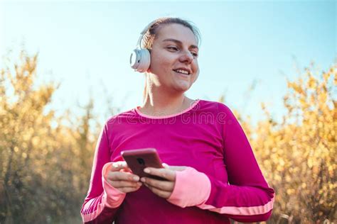 Woman Runner Running Outdoors Listening To Music On Smartphone Using