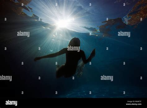 Sunbeam Silhouette Of An Underwater White Naked Girl Swimming Up Stock