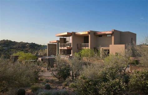 A House In The Desert Surrounded By Trees And Bushes