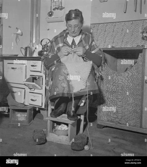 A Woman Warms Her Feet At A Foot Stove And Knits In The Meantime Stock