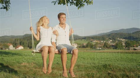 Charming Young Adults Swinging On Romantic Swing On Sunny Afternoon