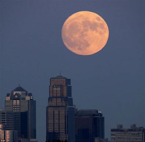 The Full Moon Is Seen In Front Of Some Tall Buildings And Skyscrapers
