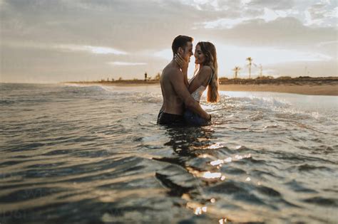 Romantic Couple Standing In Water At Beach Stock Photo