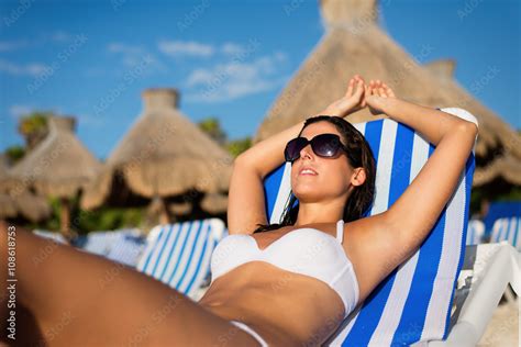 Relaxed Woman Sunbathing And Relaxing Lying On Deck Chair At Tropical Resort Beach During