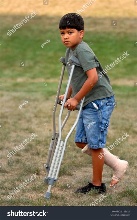 Elementary Boy Walking On Crutches With His Leg And Foot Bandaged
