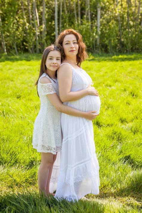 Pregnant Mother With Her Daughter White Dress In The Green Park Sunny