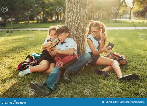 Tres Amigos De La Escuela Están Sentados Sobre El Césped Bajo Un árbol