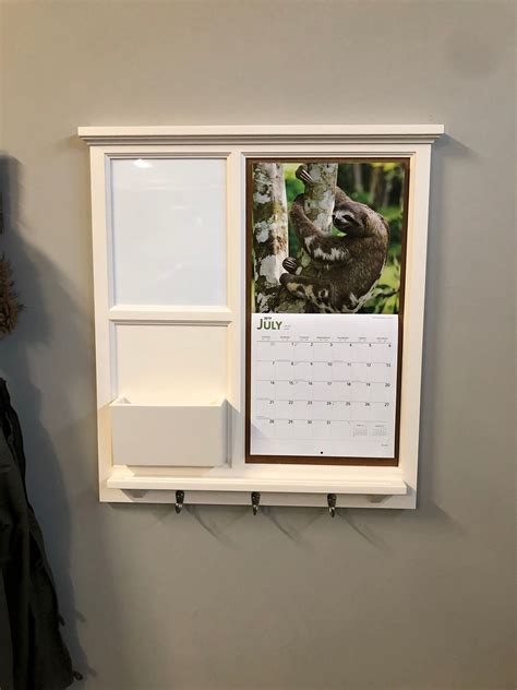 A Calendar Hanging On The Wall Next To A Window With A Slotted Slot In It
