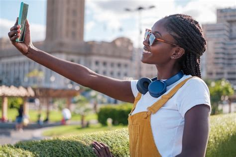 Premium Photo Young Woman In Yellow Dungarees Taking A Selfie In The City At Sunset Concept