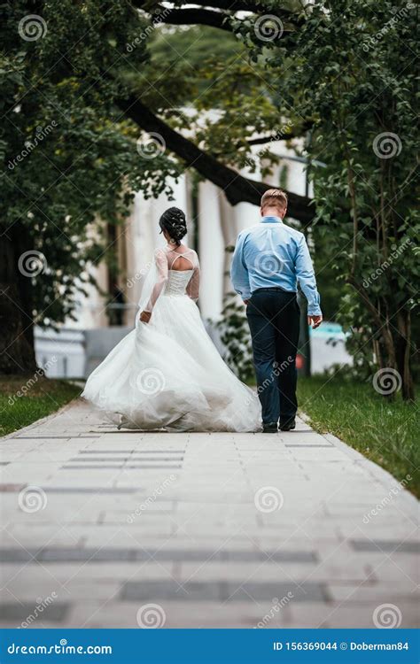 Rear View Of A Newlywed Couple Hugging In A Park Couple Goes Into The