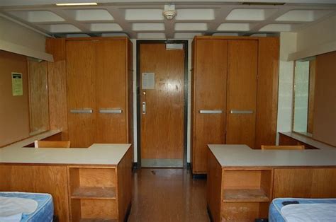 Two Beds In A Room With Wooden Cabinets And Drawers On Either Side Of