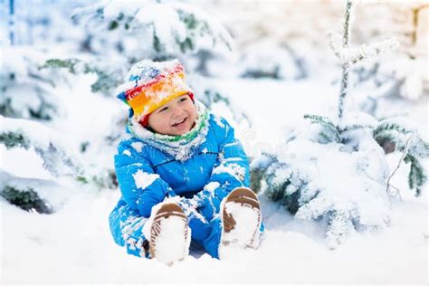 Baby Playing With Snow In Winter Child In Snowy Park Stock Photo