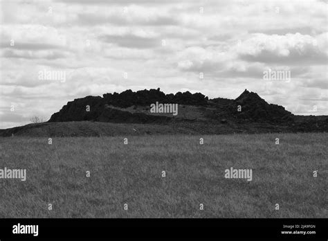 A Mound Of Dark Soil On The Park Grass In Black And White Stock Photo