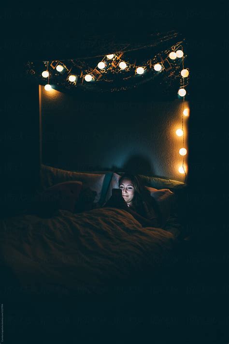 teenage girl in her room in the dark looking at her phone del colaborador de stocksy carolyn