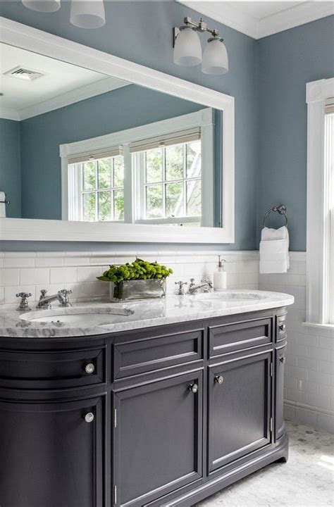 Light gray and blue runner in a white and blue master bathroom designed atop light oak floors in front of a double white washstand with bronze hardware. Classic bathroom with blue walls and deep dark vanity ...
