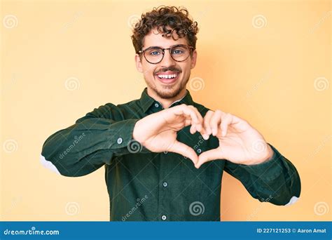 Young Caucasian Man With Curly Hair Wearing Casual Clothes And Glasses Smiling In Love Doing