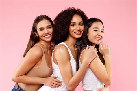 Happy Three Diverse Ladies Posing And Hugging Standing On Pink Studio