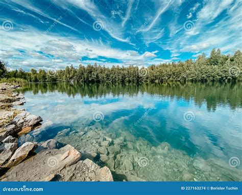 Clouds And Blue Water Are Reflected In The Forest Lake Stock Photo