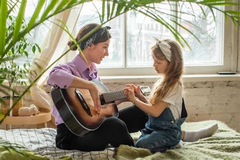 Mamá E Hija En El Sofá Tocando La Guitarra Una Mujer Y Una Niña
