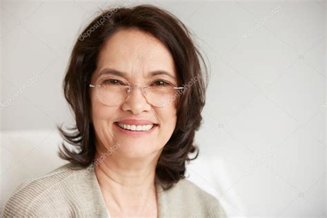 Attractive Middle Aged Brunette Woman With A Beautiful Smile Sitting Against Apartments