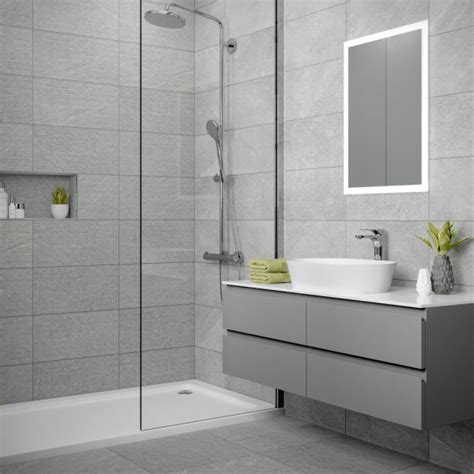 Large gray tiles on the wall lead into smaller gray tiles on the floor. Dominican Grey Wall Bathroom Tiles 250 x 500mm Per Box