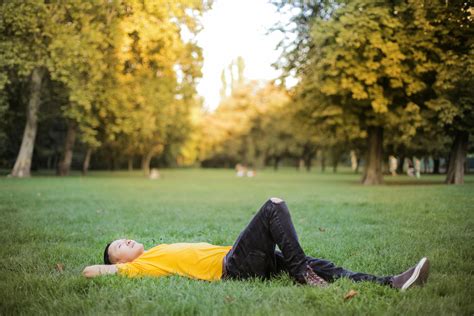 Photo Of Man In Yellow T Shirt And Black Jeans Lying Down On Green