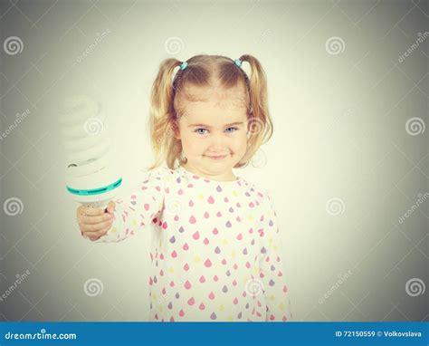 Little Girl Shows A Large Energy Saving Light Bulbs Stock Image