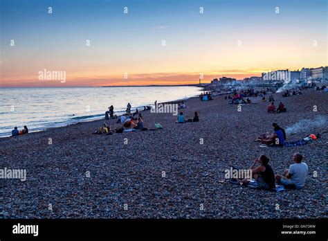 People Sitting On Brighton Beach At Sunset Brighton Sussex Uk Stock