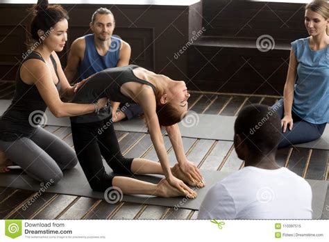 Teacher Assisting Woman Learning New Yoga Pose At Group Training Stock
