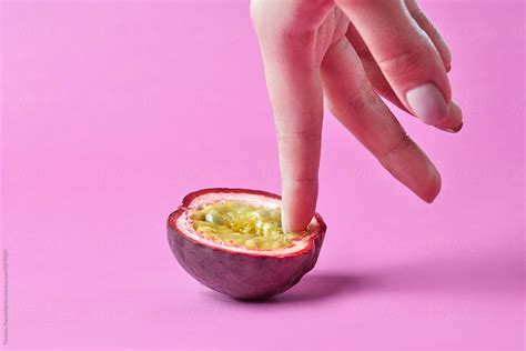 woman s finger touch inside passion exotic fruit on a pink background simulation of