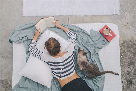 Woman Reading Book While Her Cat Is Sitting Next To Her By Jovo Jovanovic