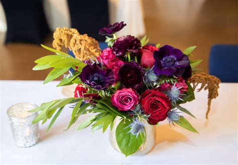 A Vase Filled With Purple And Red Flowers On Top Of A White Table Next