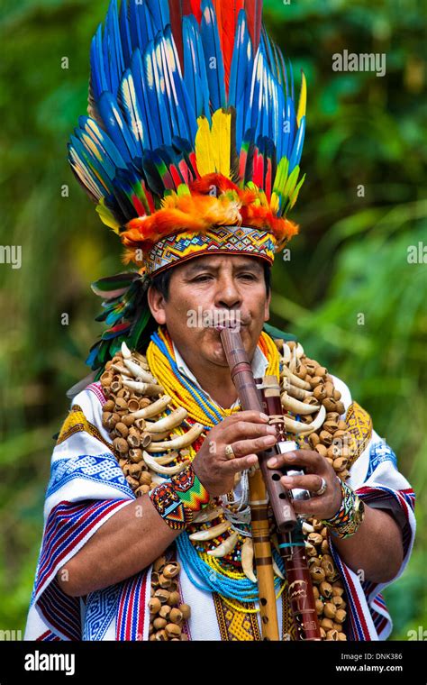 a shaman from the kamentsá tribe wearing a colorful feather headgear plays flute during the