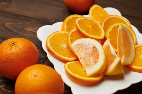 Fresh Orange Fruits Whole And Sliced On A Plate Dark Wooden Background