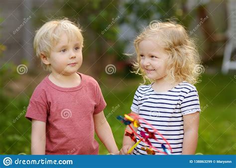 Little Boy And Girl Having Fun During Walk Happy Kids With Pinwheel