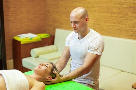 Photo Of Professional Massage Therapist Looking At Camera While Performing Massage To A Woman