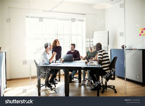 Diverse Group Of Young Designers Discussing Work Together While Sitting