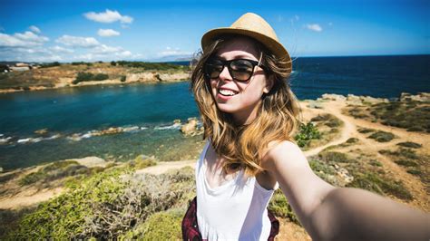 Pretty Young Female Tourist Takes Travel Selfie At The Beach While
