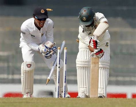 Two Men In White Uniforms Are Playing Cricket